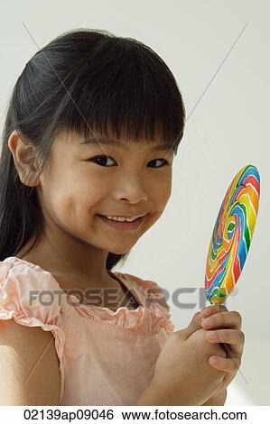 Girl with big lollipop smiling at camera View Large Photo Image Stock Photograph - Girl with big lollipop smiling at camera. Fotosearch