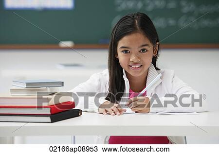 Girl with pen sitting at school desk smiling at camera View Large Photo Image Stock Image - Girl with pen sitting at school desk smiling at camera. Fotosearch