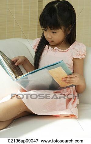 Little girl sitting on sofa reading book View Large Photo Image Stock Photo - Little girl sitting on sofa reading book. Fotosearch