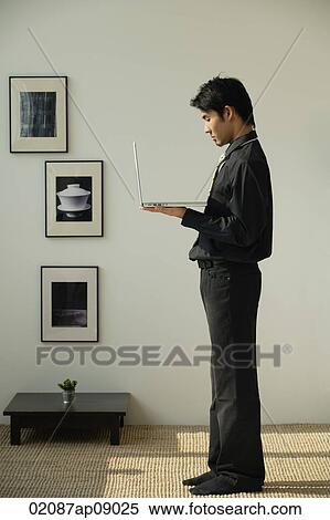 Stock Photography - Young man holding laptop. Fotosearch