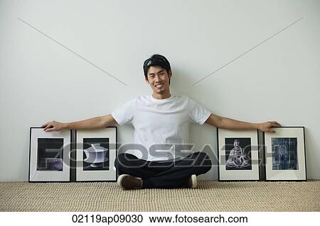 Young man sitting on floor surrounded by framed photographs View Large Photo Image Stock Image - Young man sitting on floor surrounded by framed photographs. Fotosearch
