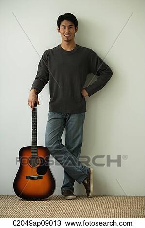 Stock Image - Young man with acoustic guitar looking at camera. Fotosearch