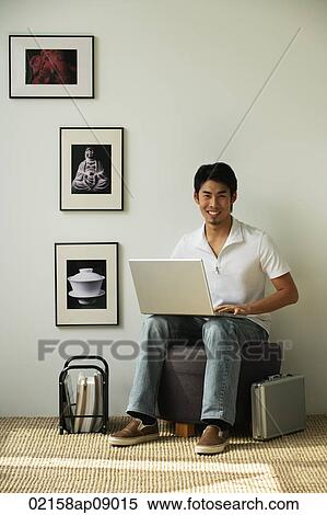 Young man with laptop on lap looking at camera View Large Photo Image Stock Photography - Young man with laptop on lap looking at camera. Fotosearch