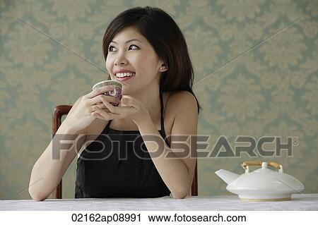 Young woman holding teacup looking sideway View Large Photo Image Stock Image - Young woman holding teacup looking sideway. Fotosearch