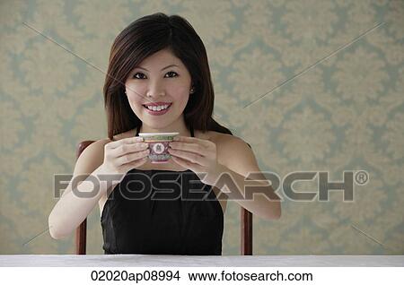 Young woman holding teacup with both hands View Large Photo Image Picture - Young woman holding teacup with both hands. Fotosearch