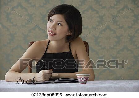 Young woman looking sideways while writing View Large Photo Image Stock Photograph - Young woman looking sideways while writing. Fotosearch