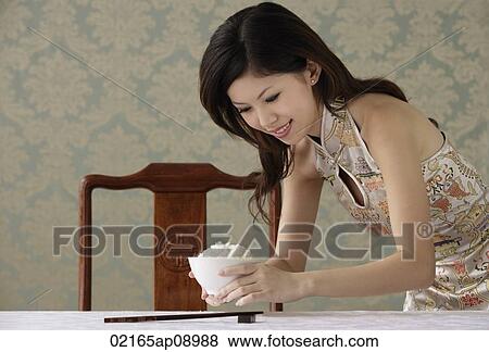 Young woman placing bowl of rice on table View Large Photo Image Stock Photo - Young woman placing bowl of rice on table. Fotosearch