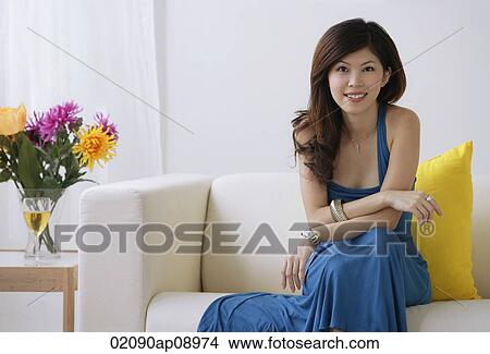 Young woman sitting on sofa View Large Photo Image Picture - Young woman sitting on sofa. Fotosearch