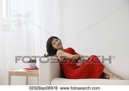 Young woman sitting on sofa View Large Photo Image Stock Photo - Young woman sitting on sofa. Fotosearch