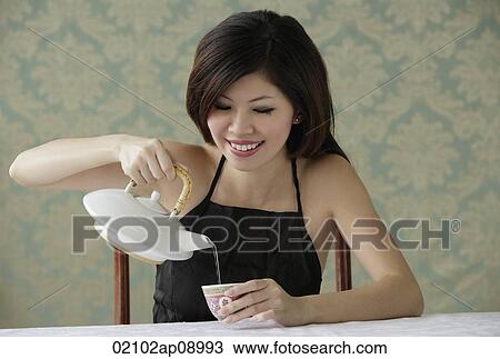 Young woman sitting pouring tea View Large Photo Image Stock Image - Young woman sitting pouring tea. Fotosearch