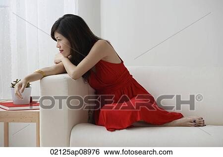Young woman sitting with legs up on sofa View Large Photo Image Stock Photograph - Young woman sitting with legs up on sofa. Fotosearch