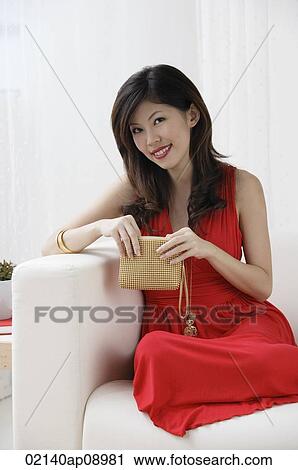 Young woman with purse sitting on sofa smiling at camera View Large Photo Image Stock Image - Young woman with purse sitting on sofa smiling at camera. Fotosearch