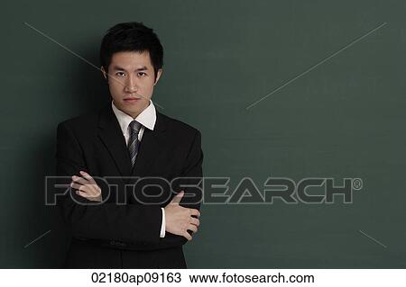 Businessman standing against black wall with arms crossed View Large Photo Image Stock Photo - Businessman standing against black wall with arms crossed. Fotosearch - Search Stock Images, Poster Photographs, Pictures, and Clip Art Photos