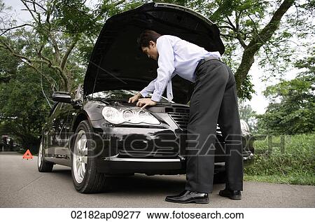 Businessman looking under hood of car View Large Photo Image Stock Photo - Businessman looking under hood of car. Fotosearch
