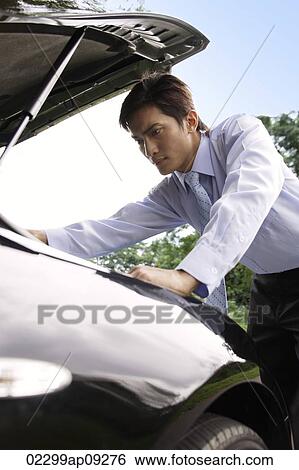 Businessman looking under hood of car View Large Photo Image Stock Photograph - Businessman looking under hood of car. Fotosearch