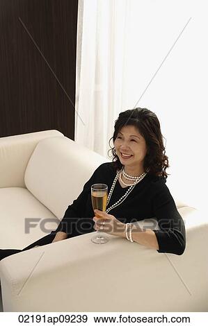 elegant woman sitting on couch with glass of champagne View Large Photo Image Stock Photo - elegant woman sitting on couch with glass of champagne. Fotosearch