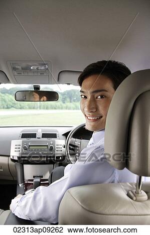 Man driving car, looking back over shoulder View Large Photo Image Stock Image - Man driving car, looking back over shoulder. Fotosearch