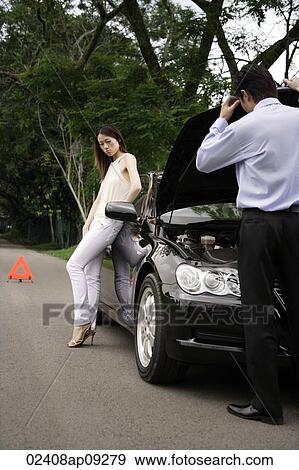 Man looking under hood of car while woman waits View Large Photo Image Stock Photo - Man looking under hood of car while woman waits. Fotosearch