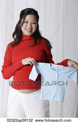 Pregnant woman holding baby clothes View Large Photo Image Stock Image - Pregnant woman holding baby clothes. Fotosearch