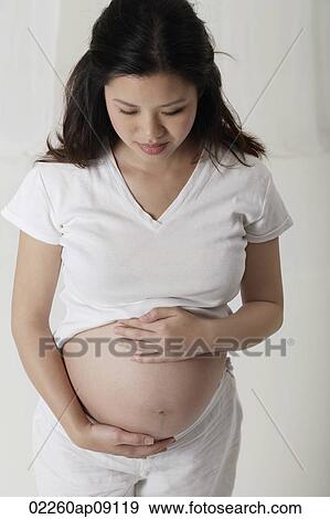 Pregnant woman holding her stomach View Large Photo Image Stock Photo - Pregnant woman holding her stomach. Fotosearch