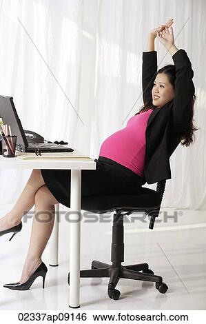 Profile of pregnant businesswoman at desk stretching View Large Photo Image Stock Photograph - Profile of pregnant businesswoman at desk stretching. Fotosearch
