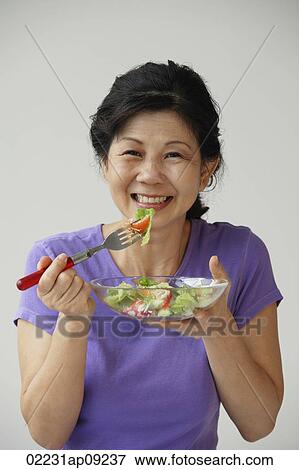 Stock Photo - Woman eating green salad. Fotosearch
