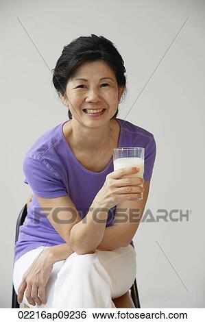 Stock Photograph - Woman holding glass of milk. Fotosearch