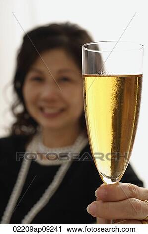 Stock Image - Woman holding up glass of champagne. Fotosearch