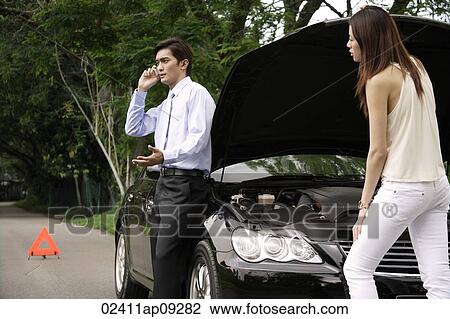 Woman looking under hood of car while man talks on phone View Large Photo Image Stock Image - Woman looking under hood of car while man talks on phone. Fotosearch