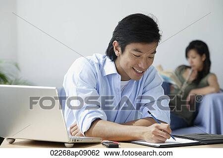 Young couple at home; man at desk; woman reading View Large Photo Image Stock Image - Young couple at home; man at desk; woman reading. Fotosearch