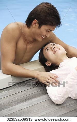 Stock Image - Young couple enjoying each other by the pool. Fotosearch