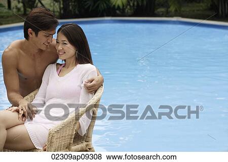 Stock Photo - Young couple enjoying each other by the pool. Fotosearch