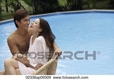 Young couple enjoying each other by the pool View Large Photo Image Stock Photo - Young couple enjoying each other by the pool. Fotosearch