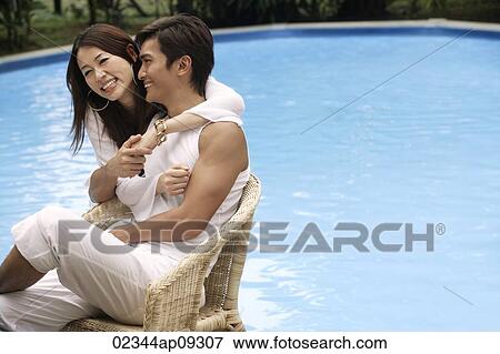 Young couple enjoying each other by the pool View Large Photo Image Stock Photo - Young couple enjoying each other by the pool. Fotosearch