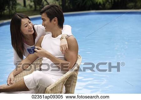 Young couple enjoying each other by the pool View Large Photo Image Stock Photography - Young couple enjoying each other by the pool. Fotosearch