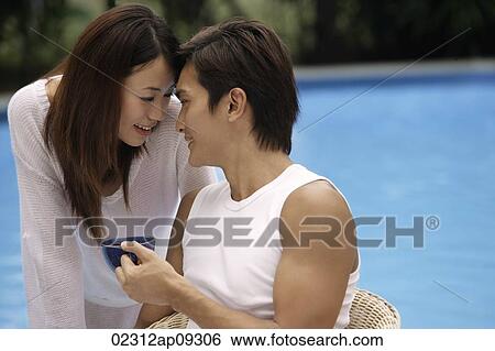 Young couple touching foreheads poolside View Large Photo Image Stock Photograph - Young couple touching foreheads poolside. Fotosearch