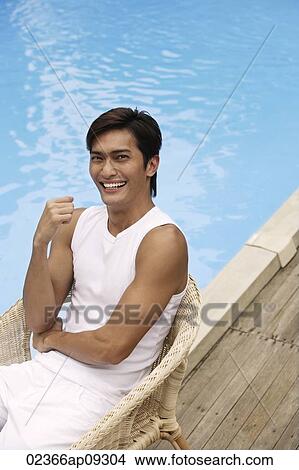 Young man sitting poolside View Large Photo Image Picture - Young man sitting poolside. Fotosearch
