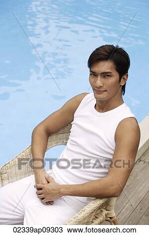 Young man sitting poolside View Large Photo Image Stock Image - Young man sitting poolside. Fotosearch