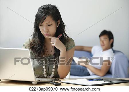 Young woman at computer, young man on couch View Large Photo Image Stock Image - Young woman at computer, young man on couch. Fotosearch