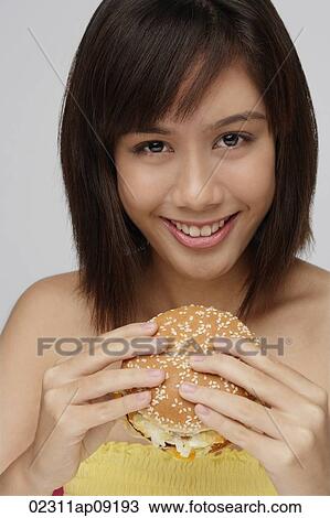 Stock Image - Young woman eating burger. Fotosearch