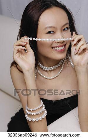 Stock Photography - Young woman holding strand of pearls. Fotosearch