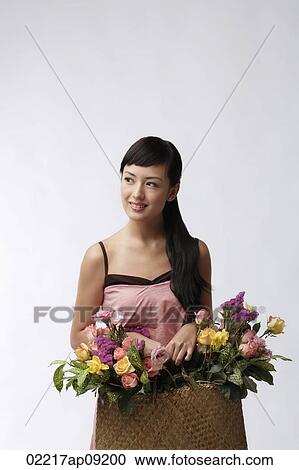 Young woman holding straw bag full of flowers View Large Photo Image Stock Image - Young woman holding straw bag full of flowers. Fotosearch
