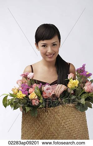 Young woman holding straw bag full of flowers View Large Photo Image Stock Image - Young woman holding straw bag full of flowers. Fotosearch