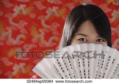 Chinese woman looking over hand-held fan with Chinese characters View Large Photo Image Picture - Chinese woman looking over hand-held fan with Chinese characters. Fotosearch