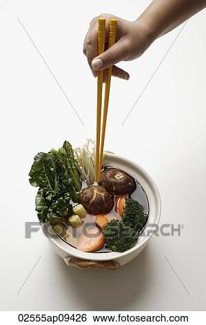 hand holding chopsticks in clay pot of vegetables View Large Photo Image Stock Photograph - hand holding chopsticks in clay pot of vegetables. Fotosearch