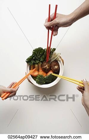 hands holding chopsticks in clay pot of vegetables View Large Photo Image Stock Photo - hands holding chopsticks in clay pot of vegetables. Fotosearch