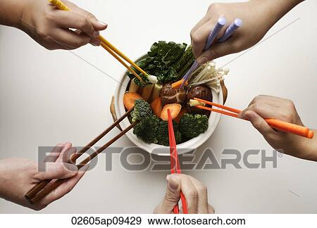 hands holding chopsticks in clay pot of vegetables View Large Photo Image Stock Photo - hands holding chopsticks in clay pot of vegetables. Fotosearch