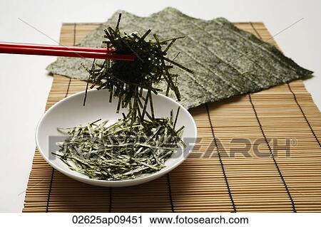 seaweed shreds picked up by red chopstick with seaweed sheets in background View Large Photo Image Stock Image - seaweed shreds picked up by red chopstick with seaweed sheets in background. Fotosearch