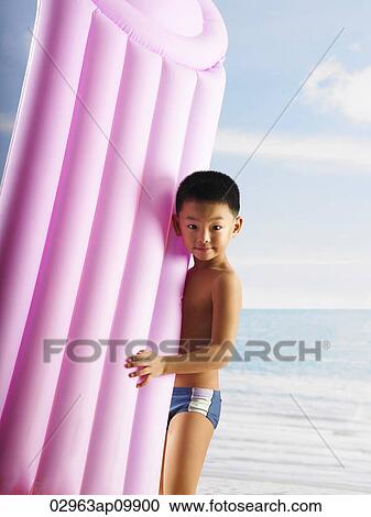 Stock Image - boy holding inflatable raft. Fotosearch