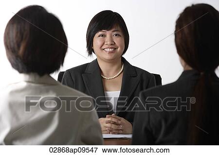 Stock Photo - business woman sitting at desk smiling. Fotosearch